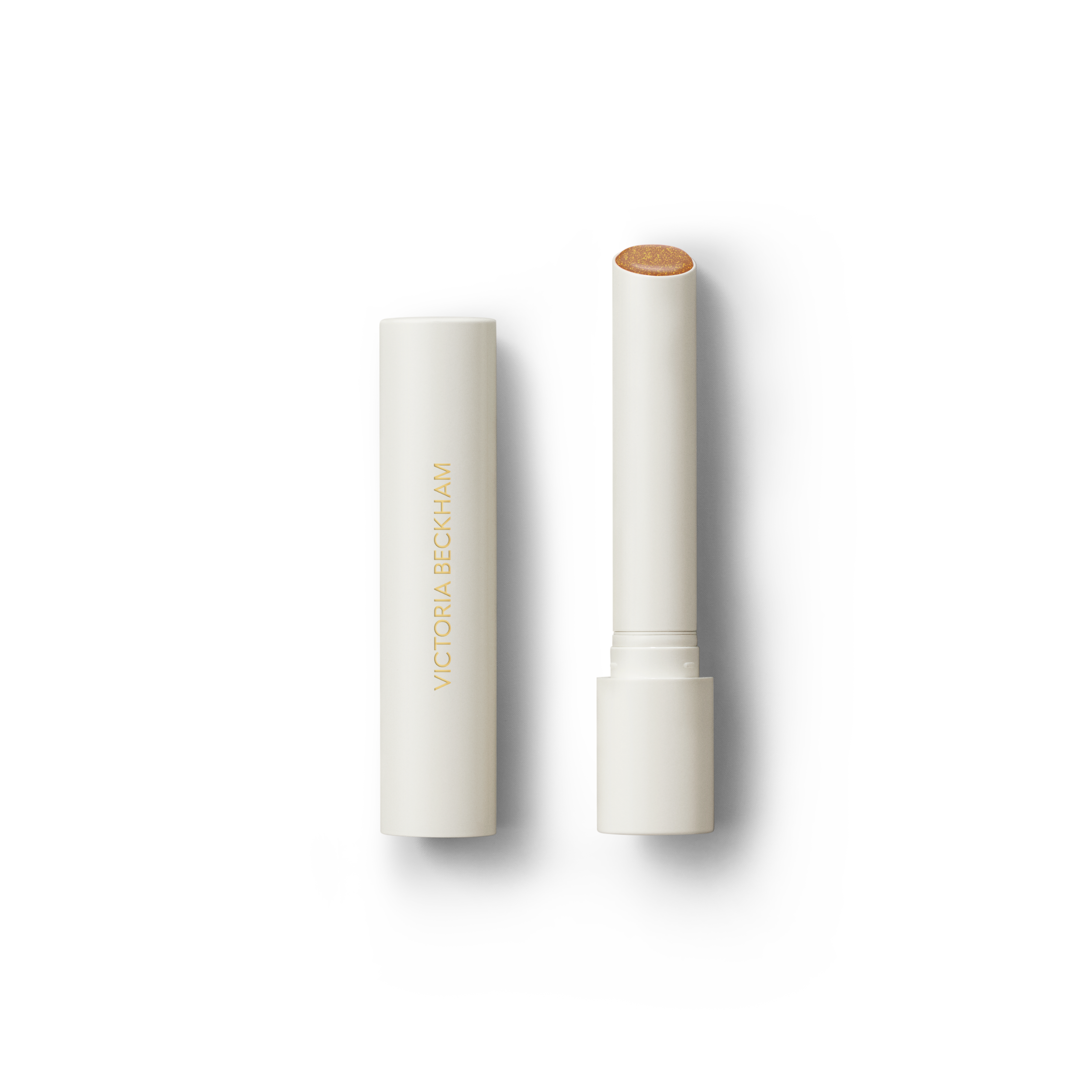 Open Victoria Beckham Beauty Posh Balm in Soleil — cream tube and cap beside the golden bronze shimmer balm bullet.