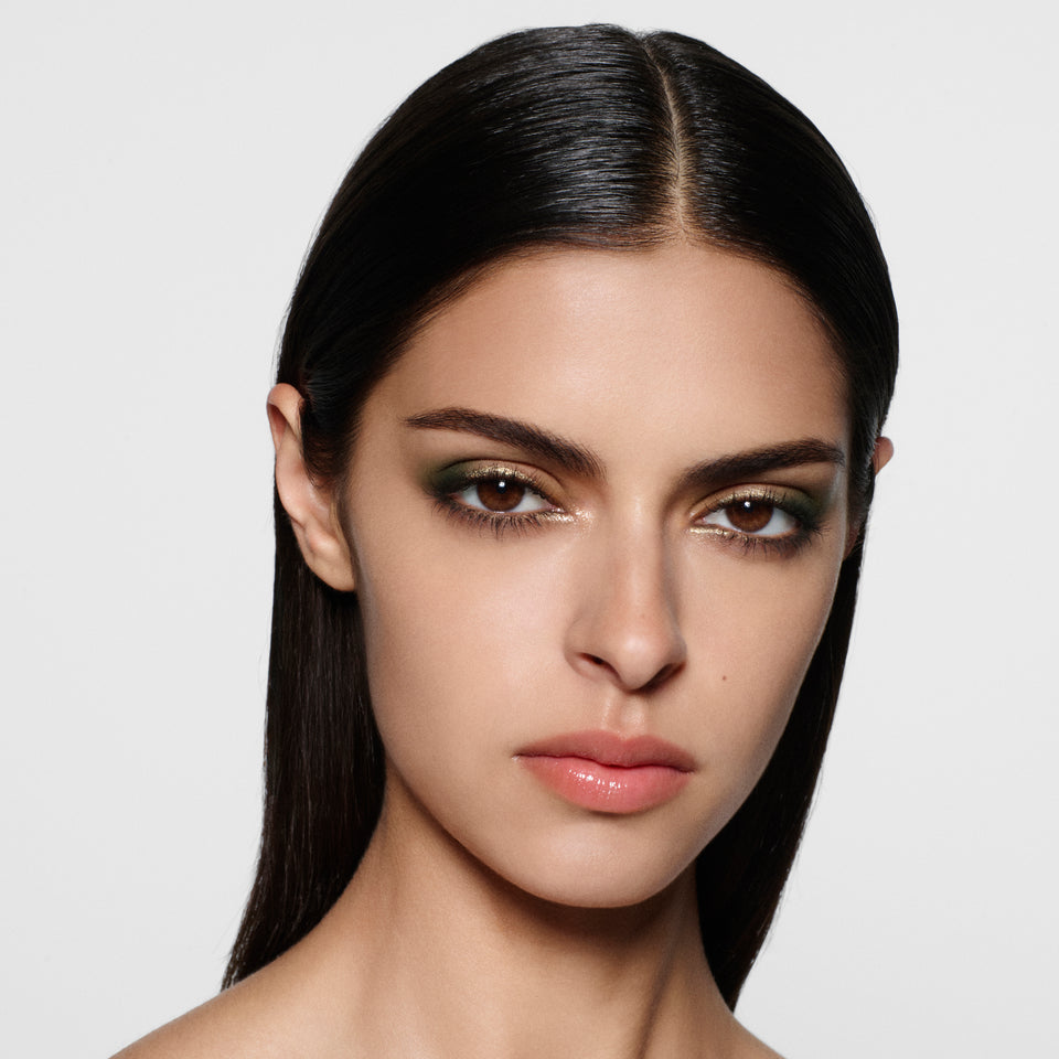 Olive-complexion model with long sleek centre-parted dark hair in an olive smoky eye — Victoria Beckham Beauty Olive Eye Kit look.