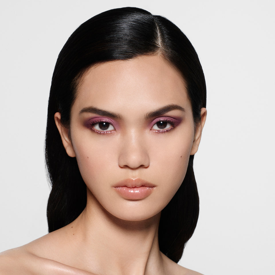 Model with sleek tucked-back dark hair wearing an orchid violet shimmer eye — Victoria Beckham Beauty Orchid Eye Kit look.