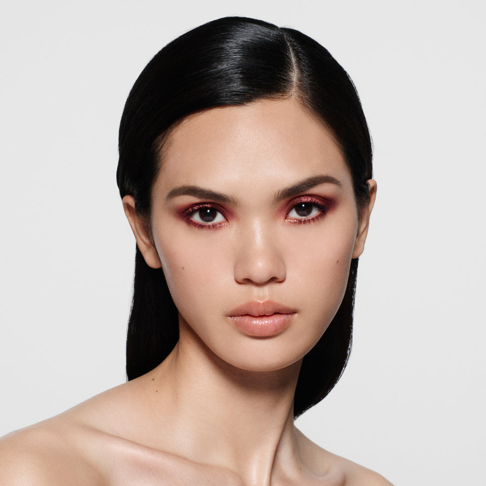 Model with sleek tucked-back dark hair wearing a burgundy shimmer eye — Victoria Beckham Beauty Bordeaux Eye Kit look.