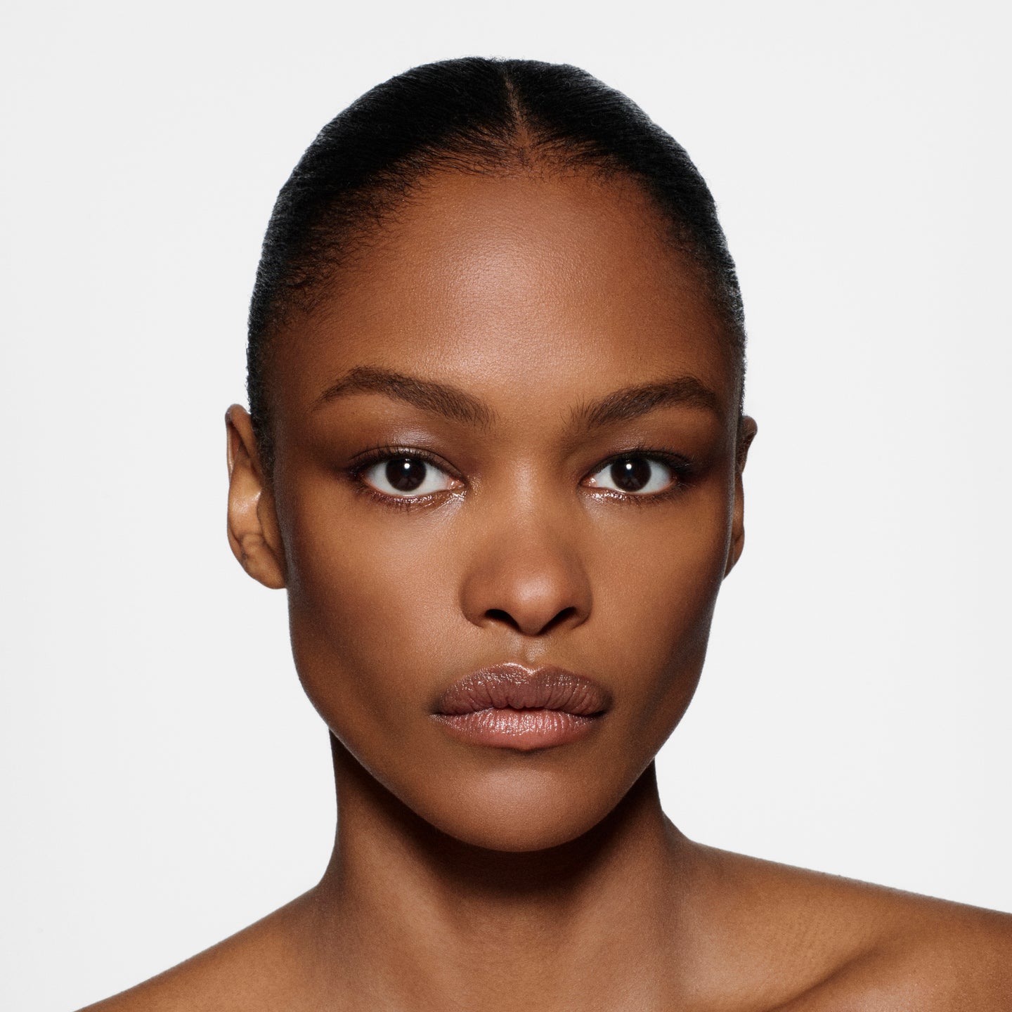 Close-up of a woman's face with a neutral expression on a white background