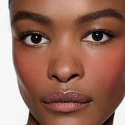 Close-up of cheek on medium-brown complexion in Blush Stylus Rossa — Victoria Beckham Beauty dusty rose pink blush.