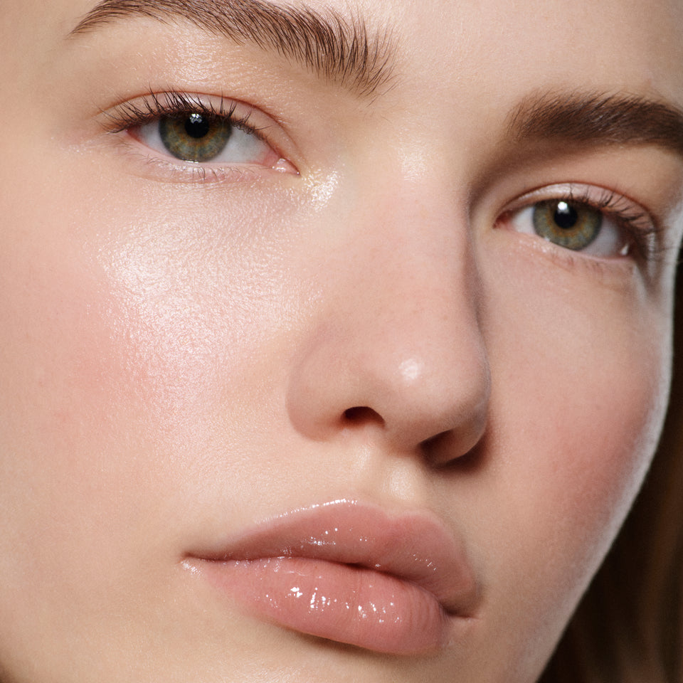 Close-up of fair lips glossed in Posh Gloss Bikini — Victoria Beckham Beauty's milky peach nude with mirror-shine finish.