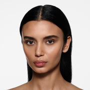 Olive-complexion model with long sleek dark hair wearing Posh Gloss Cabana — dusty rose pink by Victoria Beckham Beauty.