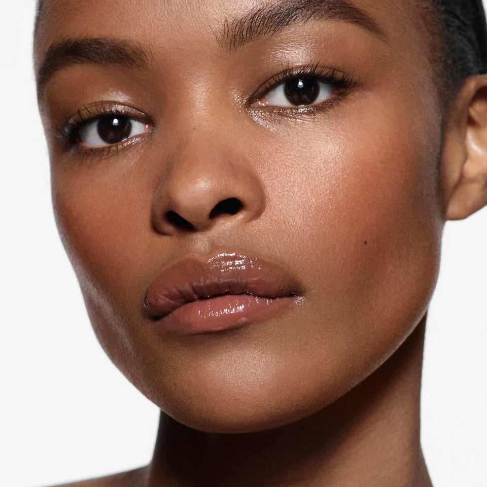 Close-up of brown lips in Posh Gloss Poolside — Victoria Beckham Beauty's cocoa brown high-shine lip gloss.