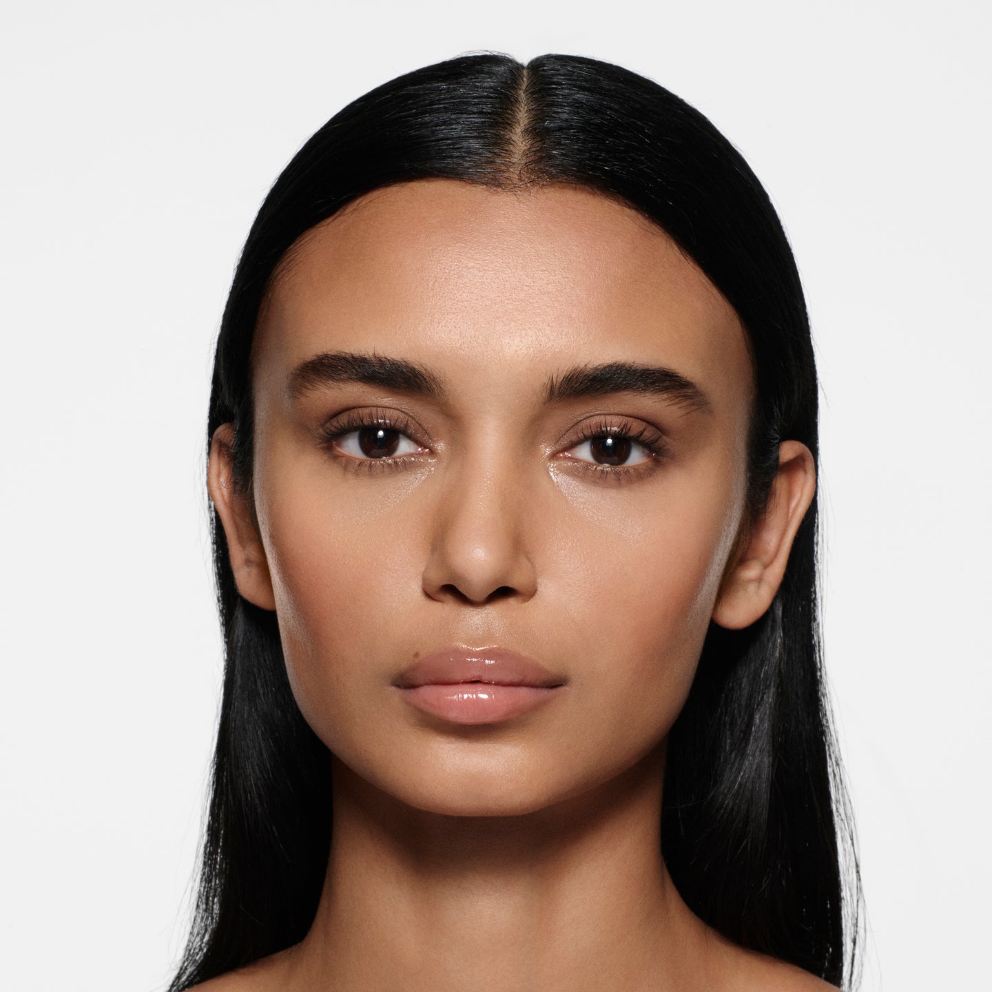 Olive-complexion model with long centre-parted dark hair in Posh Gloss Bikini — milky peach nude by Victoria Beckham Beauty.
