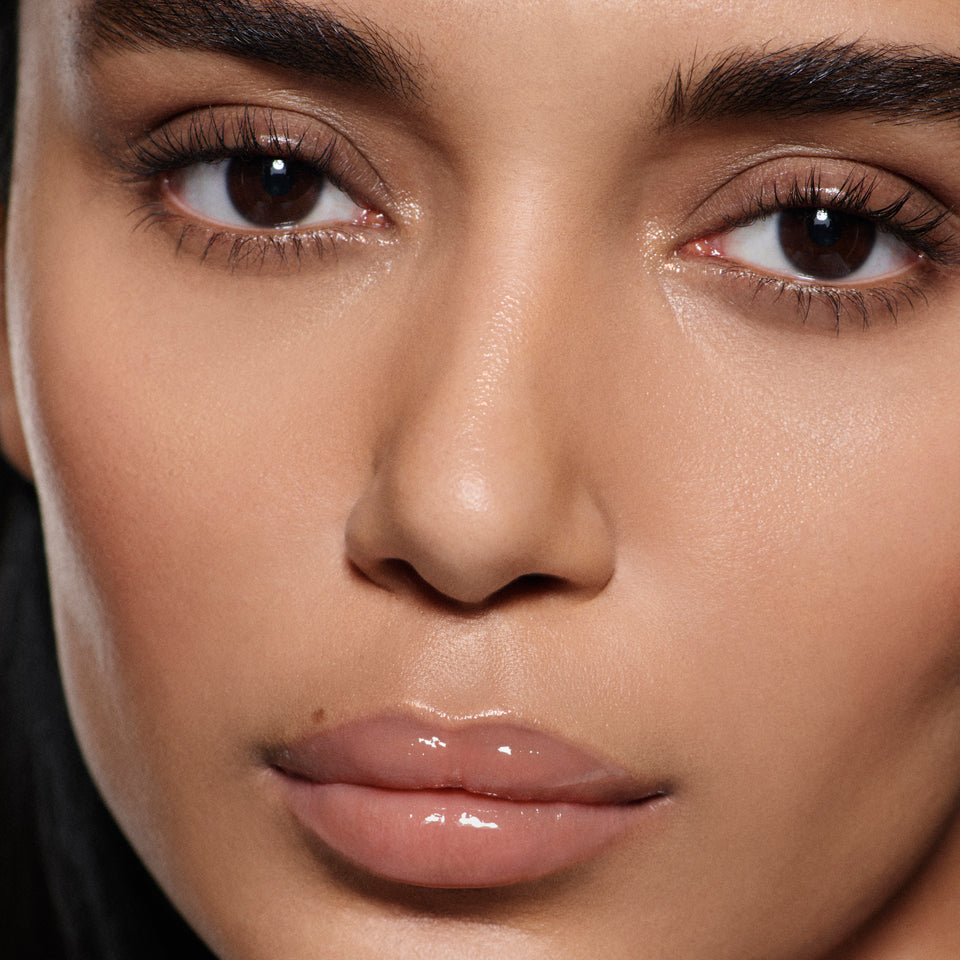 Close-up of lips on olive complexion in Posh Gloss Bikini, Victoria Beckham Beauty's milky peach nude high-shine gloss.
