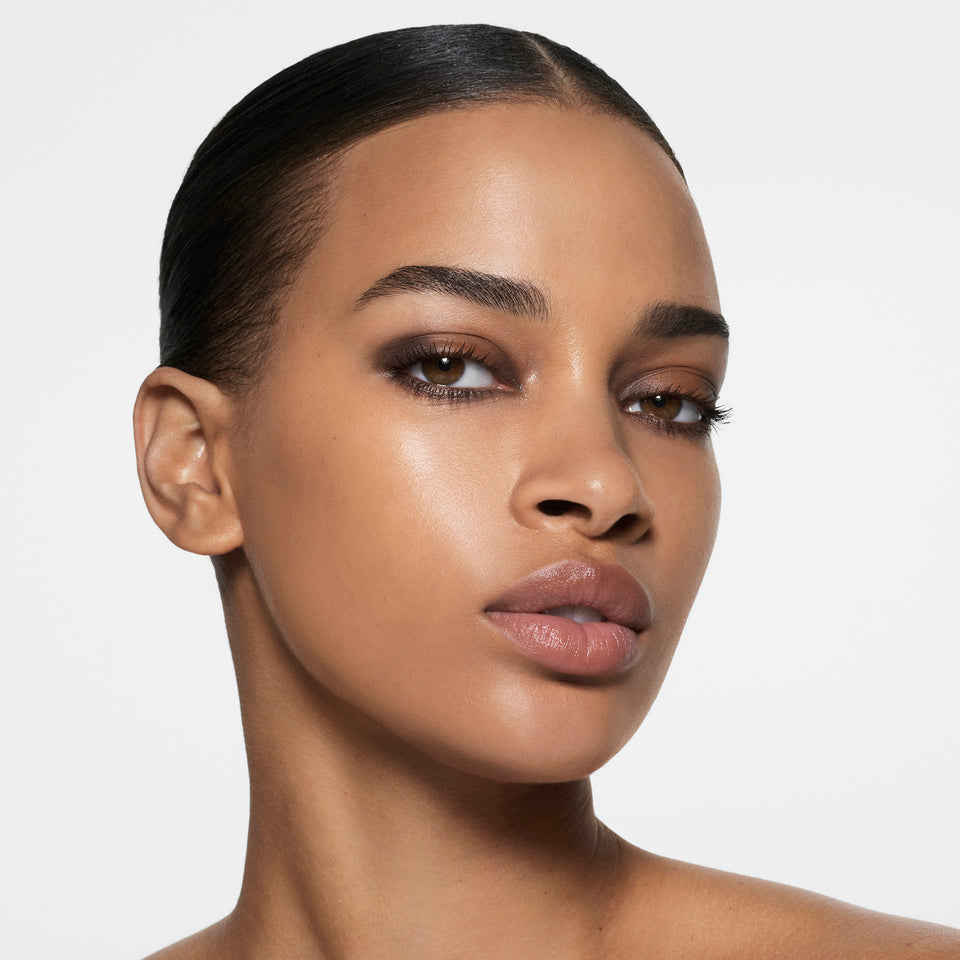Deep-complexion model with slicked-back hair in a soft cocoa smoky eye — Victoria Beckham Beauty Cocoa Eye Edit.