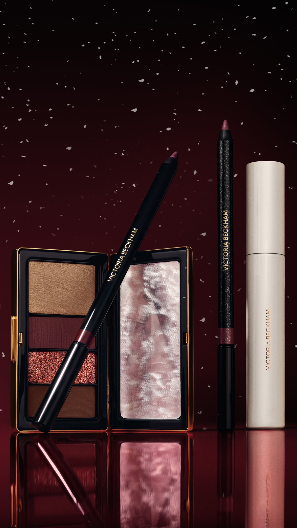 Eyeshadow quad, eyeliner and mascara on a snowy burgundy backdrop — Victoria Beckham Beauty holiday eye collection.