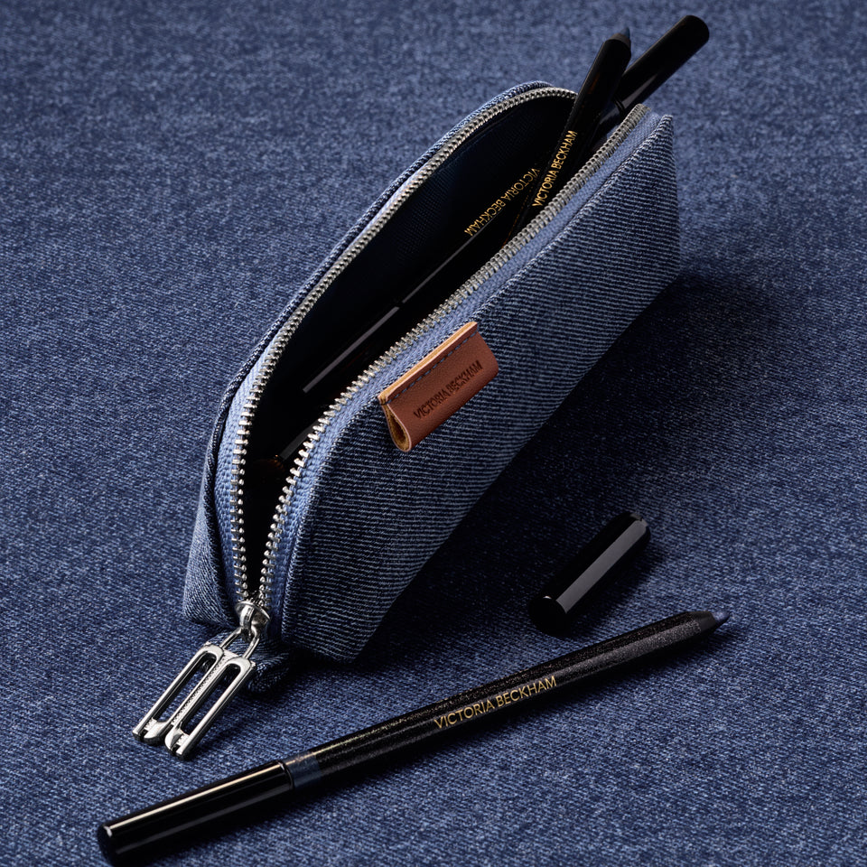 A blue denim pencil case with a silver zipper, shown open with cosmetic pens inside. 