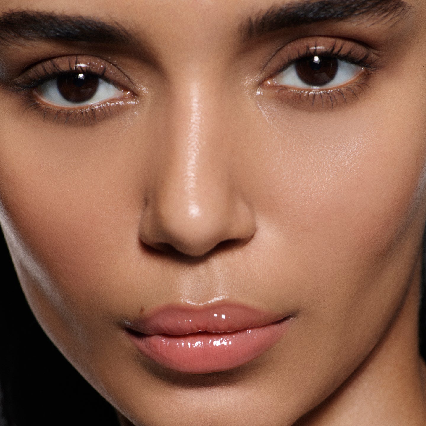 Close-up of lips on olive complexion in Posh Gloss Bungalow, Victoria Beckham Beauty's warm coral peach high-shine gloss.