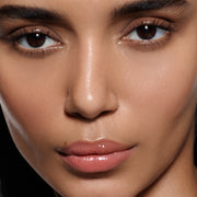 Close-up of lips on olive complexion in Posh Gloss Bungalow, Victoria Beckham Beauty's warm coral peach high-shine gloss.