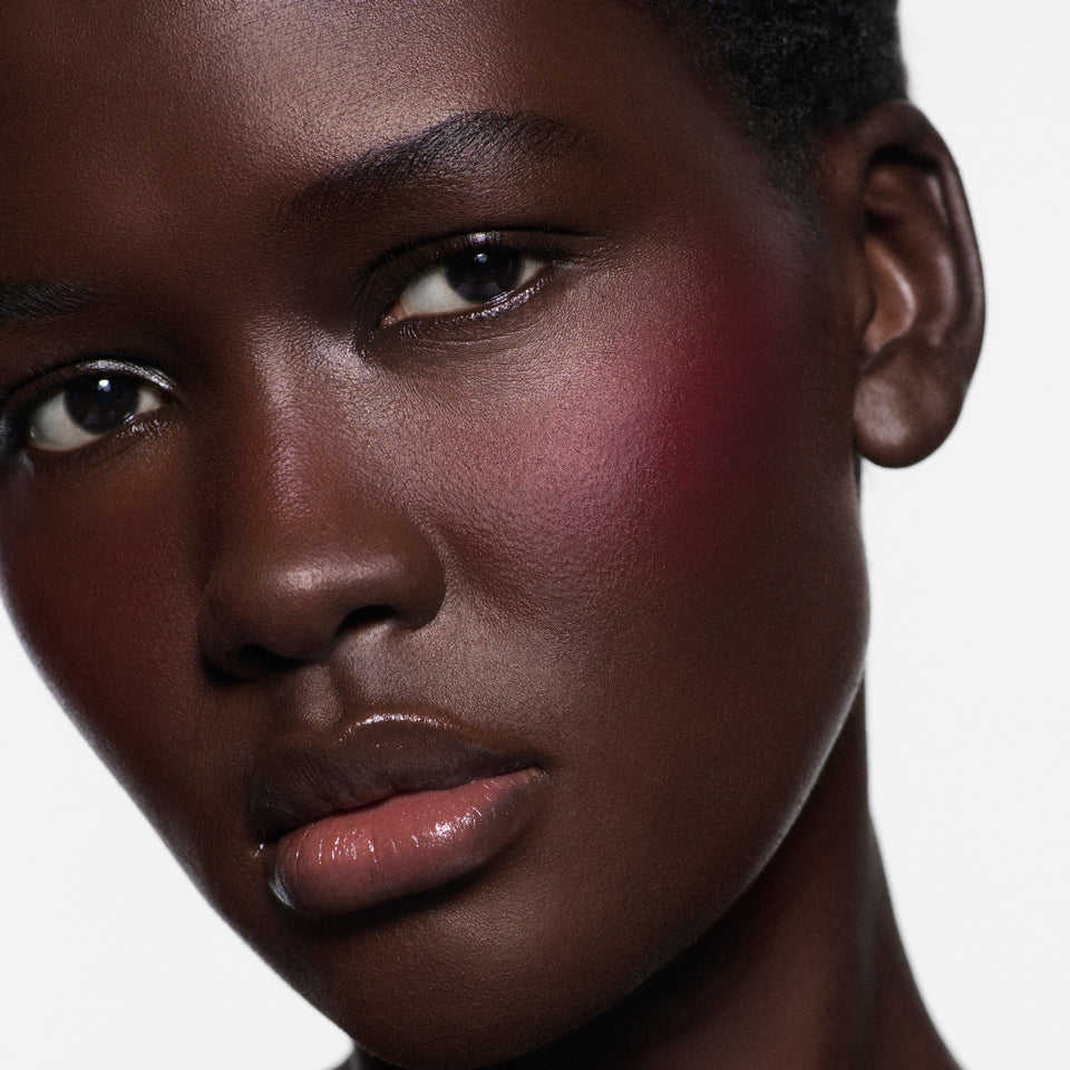 Close-up of cheek on deep complexion in Blush Stylus Fiore — Victoria Beckham Beauty's creamy blush stick in fuchsia.