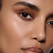 Close-up of a tan-complexion eye with defined cocoa-brown lashes in Vast Lash Cocoa by Victoria Beckham Beauty.