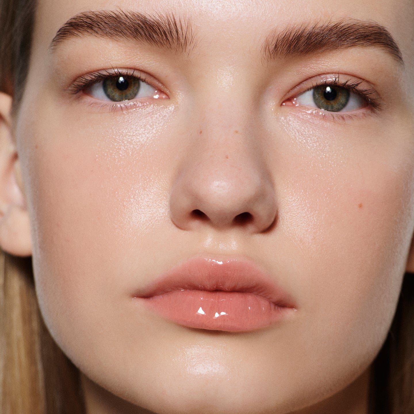 Close-up of fair lips in Posh Gloss Picante — Victoria Beckham Beauty's vivid coral salmon high-shine lip gloss.