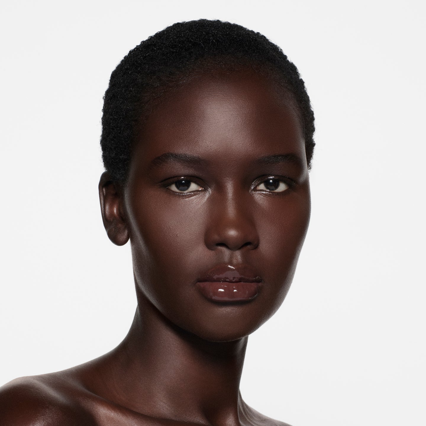Deep-cocoa complexion with short cropped natural hair, lips in Posh Gloss TopDown — deep mahogany by Victoria Beckham Beauty.