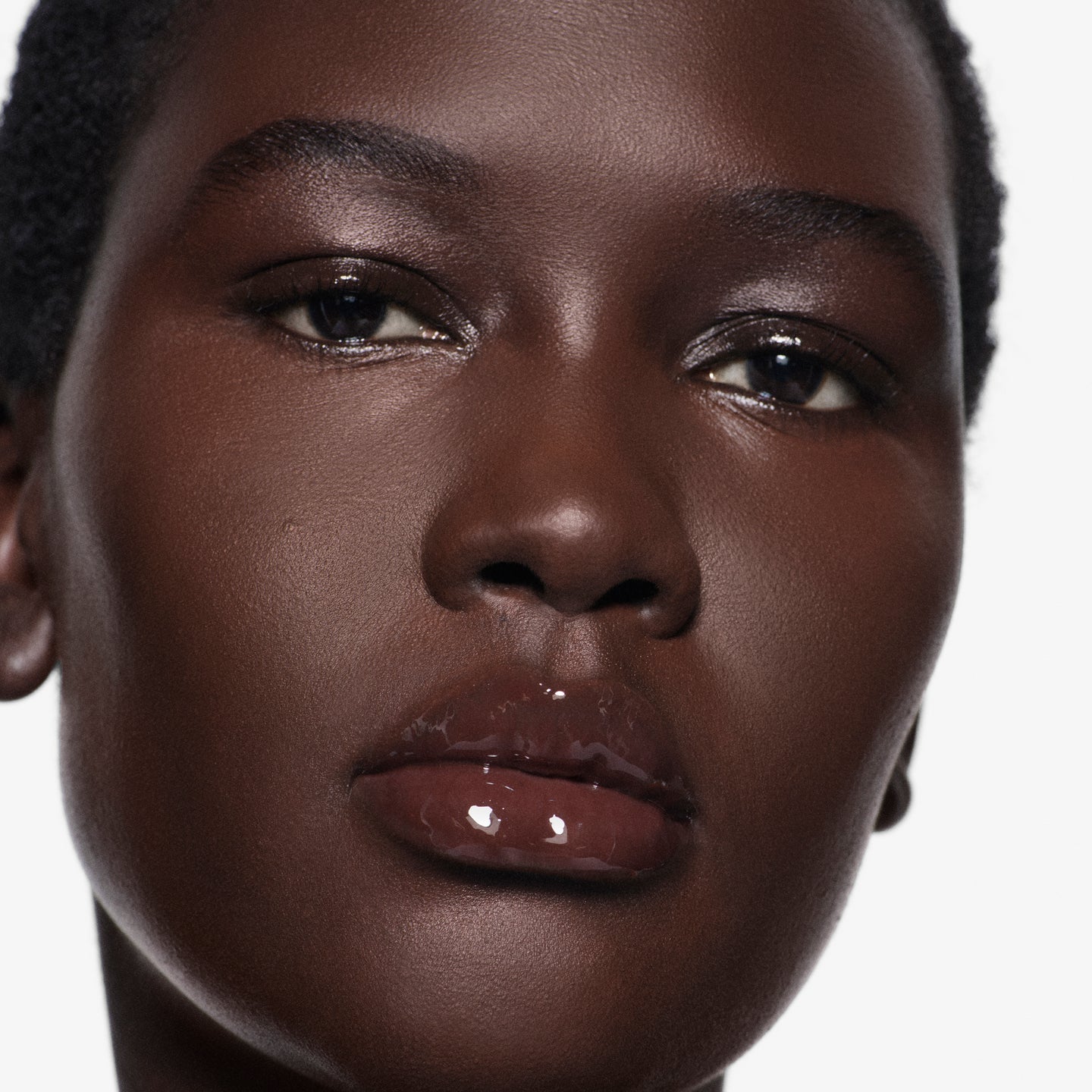 Close-up of lips on deep complexion in Posh Gloss TopDown — Victoria Beckham Beauty's deep mahogany mirror-shine gloss.