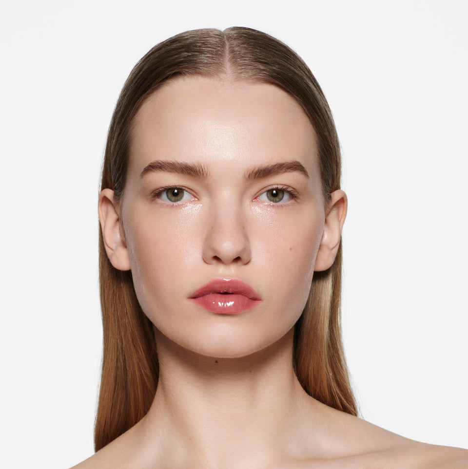 Fair-skinned model with slicked-back dirty-blonde hair wearing Posh Gloss Cabana — dusty rose pink by Victoria Beckham Beauty.