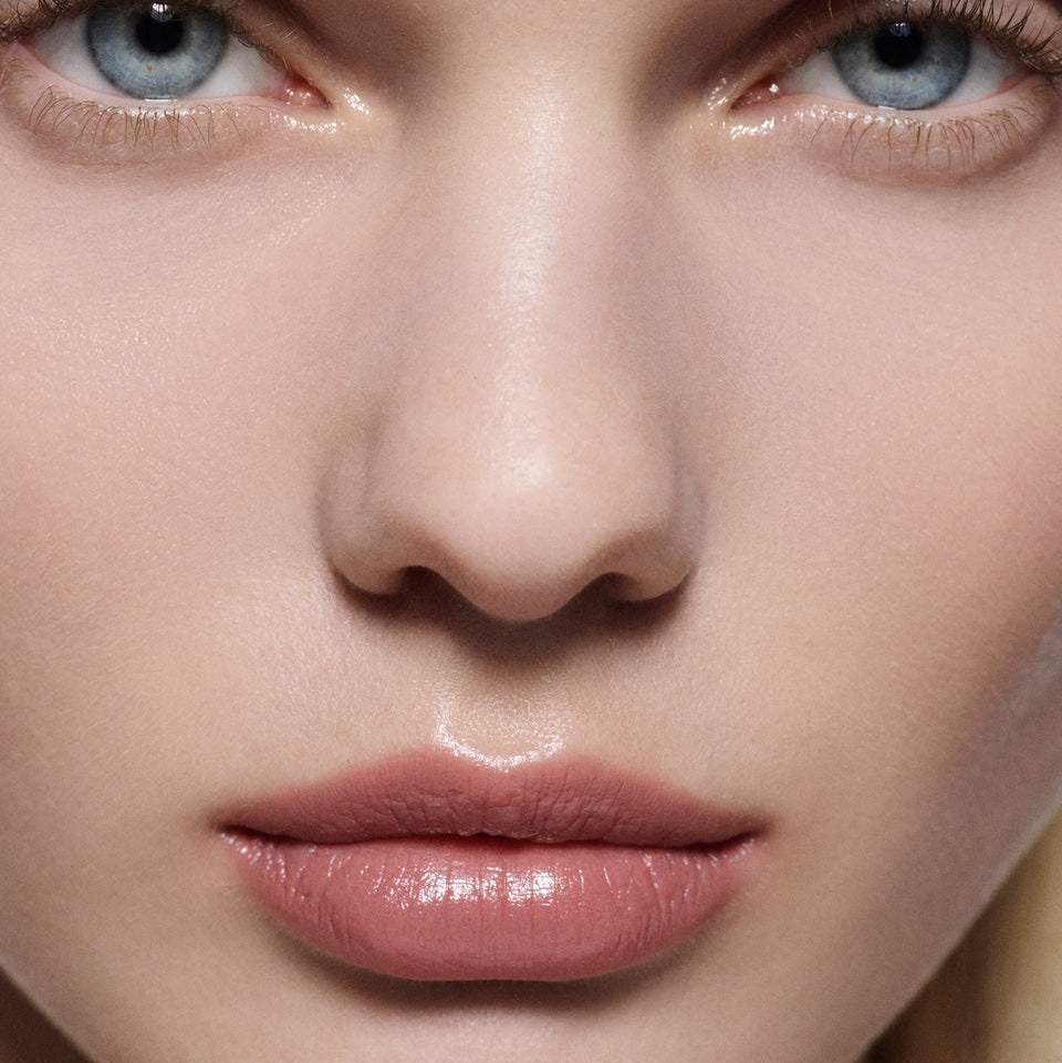Close-up of fair lips wearing a soft rose nude Posh Lip — Victoria Beckham Beauty lipstick with a satin sheen.