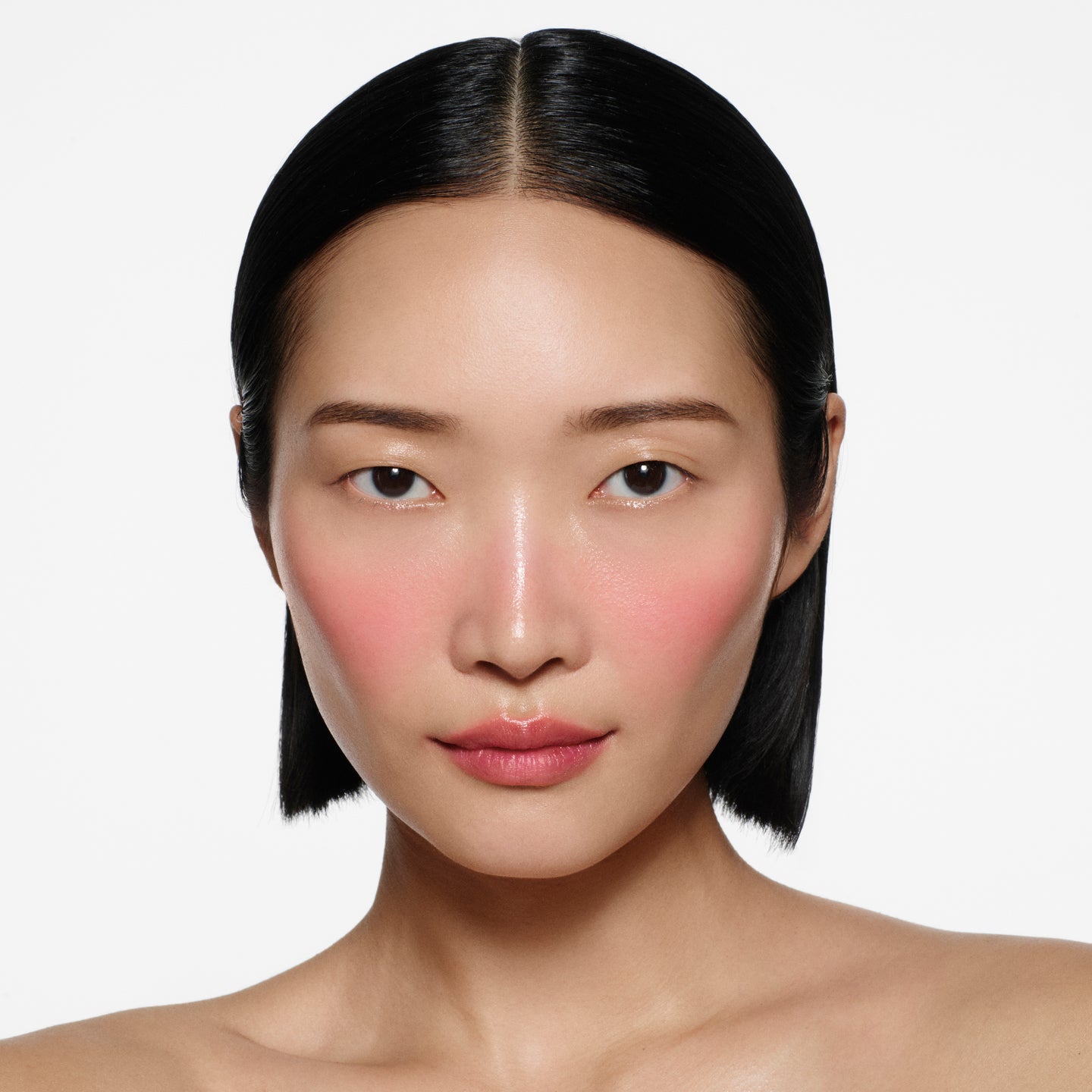 East Asian model with sleek dark bob, rosy pink flush on cheeks in Blush Stylus Fiore by Victoria Beckham Beauty.