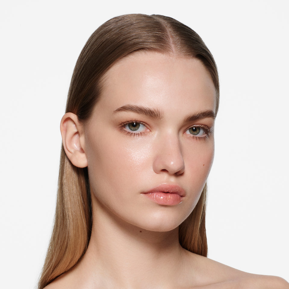 Fair-complexion model with long centre-parted hair wearing Posh Balm Soleil and Vast Lash Cocoa by Victoria Beckham Beauty.