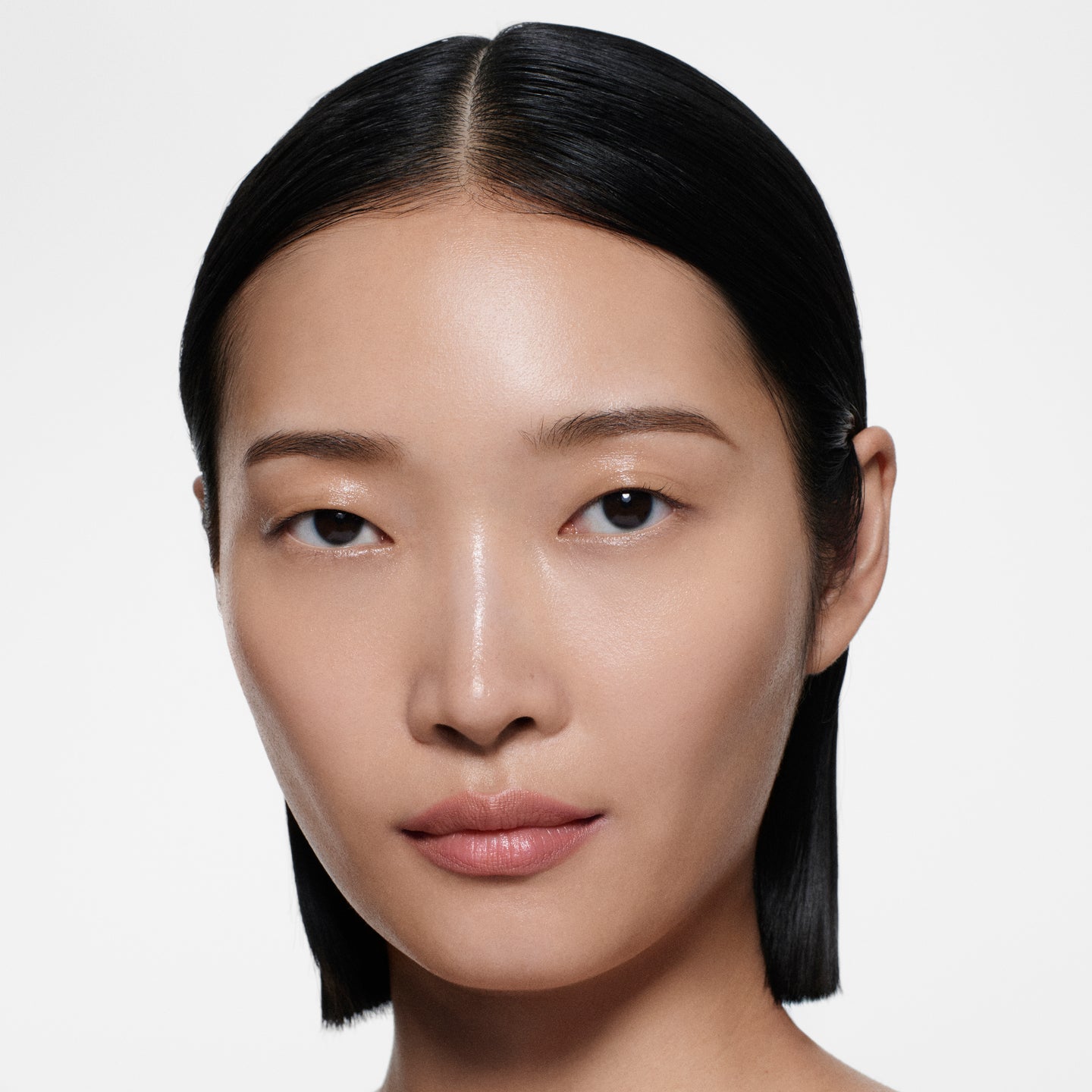 Warm-tan model with sleek centre-parted dark hair in Lip Definer No. 01 — dusty peach-rose by Victoria Beckham Beauty.