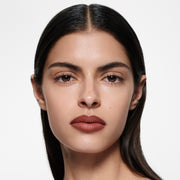 Olive-complexion model with sleek centre-parted dark hair in Lip Definer No. 04 — brick red-brown by Victoria Beckham Beauty.