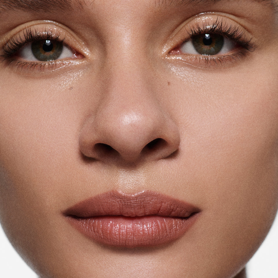 Close-up of tan lips lined in Lip Definer No. 02 — Victoria Beckham Beauty's warm rosewood lip pencil.