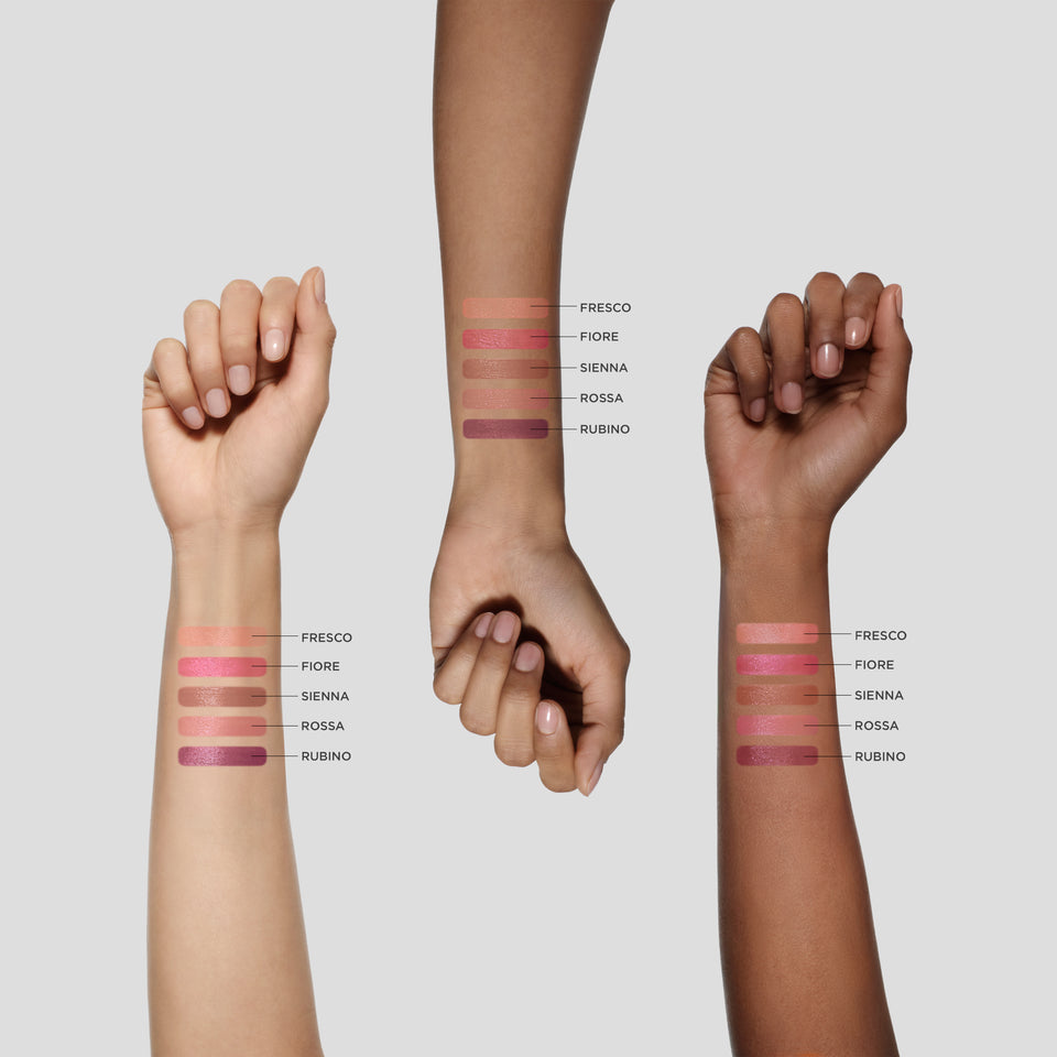 Three hands with different skin tones displaying swatches of pink makeup on a light gray background.