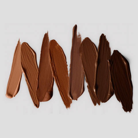 Victoria Beckham Beauty concealer swatches in a gradient of shades from medium dark to deep, showcasing the creamy and blendable texture on a neutral background.