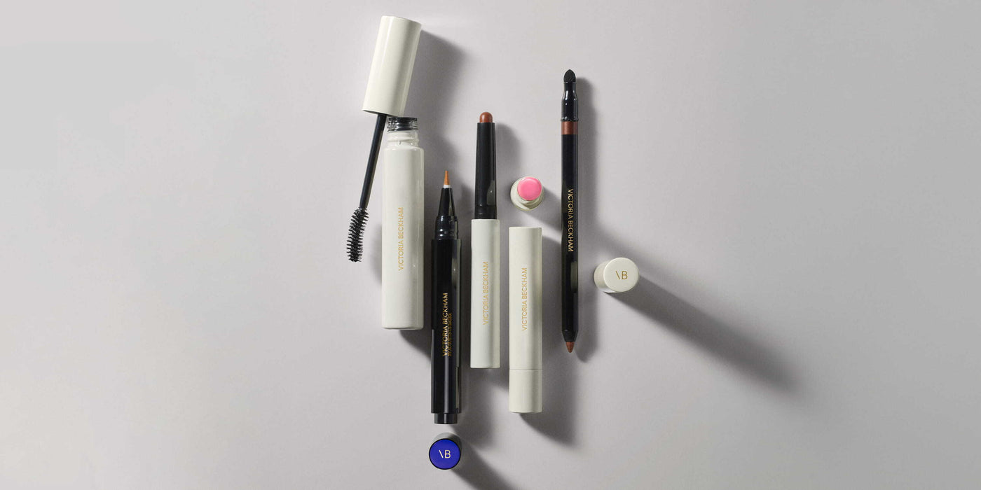 Set of makeup products including mascara, eyeliner, and other products on a light gray background
