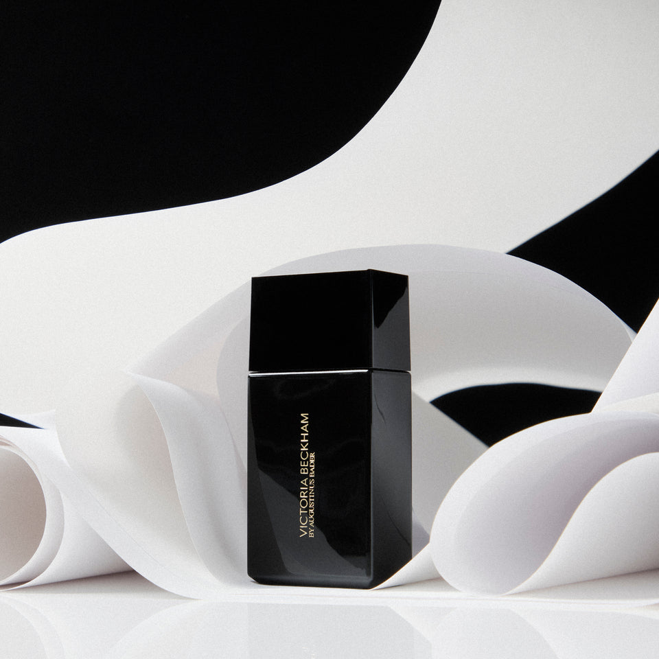 Black square Victoria Beckham by Augustinus Bader bottle on curling paper in a black-and-white composition.