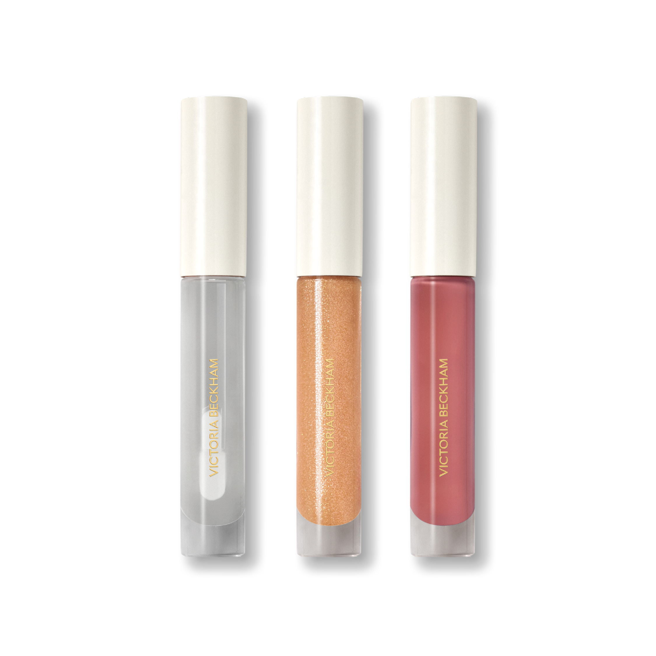 Three Posh Gloss tubes on black — Ice, Martini and Cabana from Victoria Beckham Beauty's high-shine lip gloss range.
