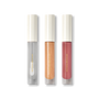 Three Posh Gloss tubes on black — Ice, Martini and Cabana from Victoria Beckham Beauty's high-shine lip gloss range.