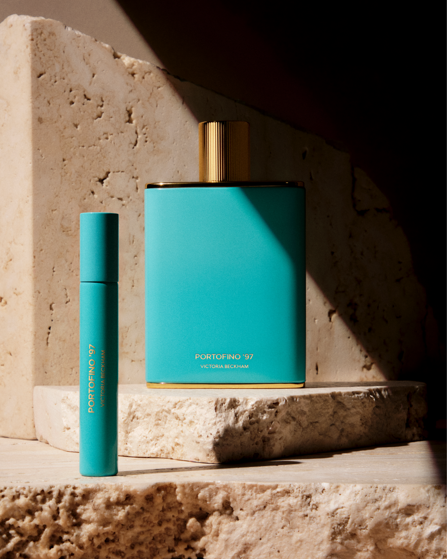 Two turquoise perfume bottles with gold caps on a stone surface