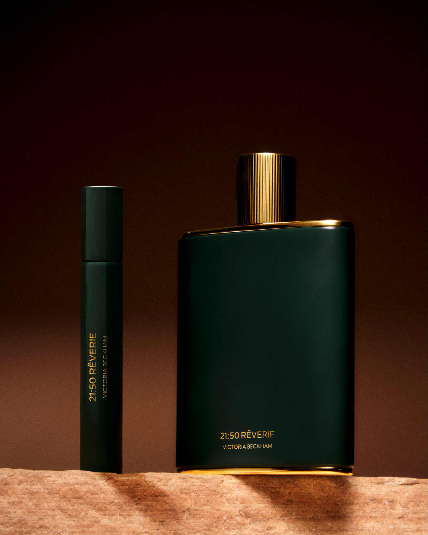 Two dark green perfume bottles with gold accents on a brown background