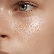 A close-up of a model's cheek and eye, showing glowing skin.
