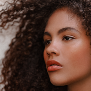 An image of a model's face with curly hair.