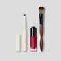 Makeup products including a lip gloss, a brush, and a lipstick on a light gray background