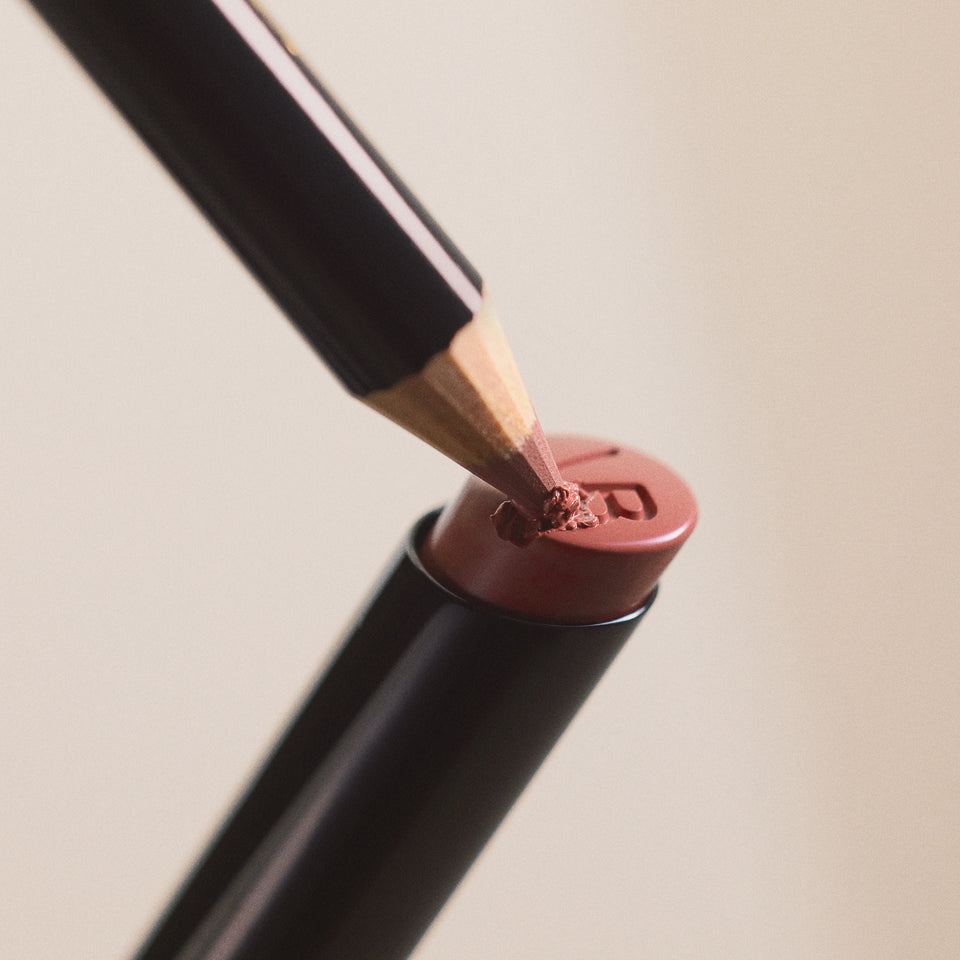 Close-up of a makeup pencil with pink powder on a beige background