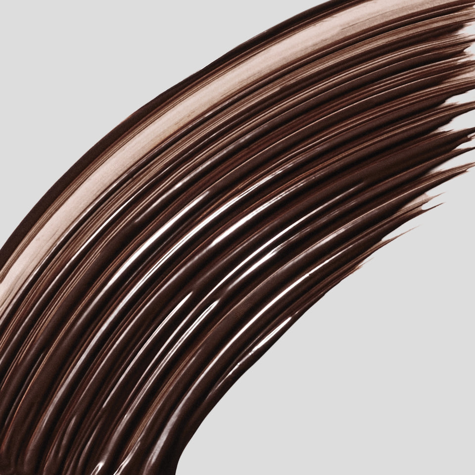 Macro cocoa-brown mascara swatch on grey — Victoria Beckham Beauty Vast Lash in Cocoa, a buildable lash mascara.