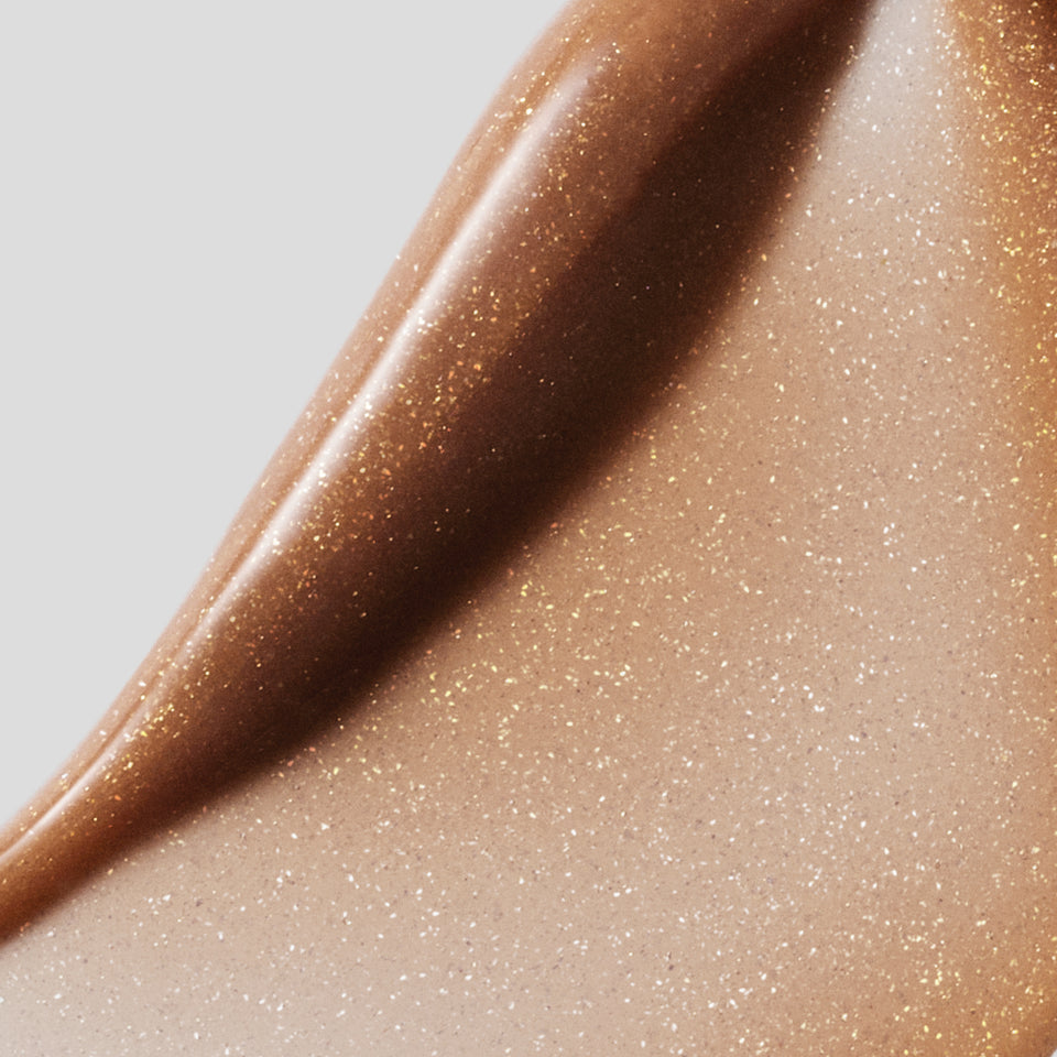 Macro golden bronze balm swatch with gold shimmer on grey — Victoria Beckham Beauty Posh Balm Soleil tinted balm.
