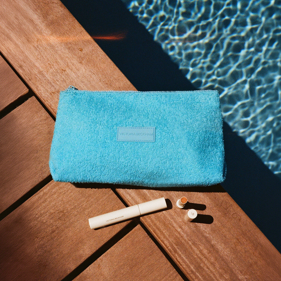 Turquoise terry pouch poolside with Posh Balm Soleil and Vast Lash mascara — Victoria Beckham Beauty summer gift.