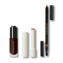 The Foundation Drops, a cream-cased nude lipstick and a Lip Definer pencil on grey — Victoria Beckham Beauty Ultimate Trio.