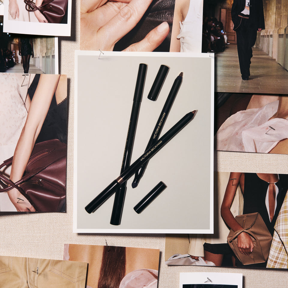 A set of black makeup pencils, including two cap-ended pencils, arranged on a white card pinned to a beige fabric collage board. The board is decorated with various fashion and lifestyle photos.