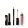 A set of three Victoria Beckham Beauty lip products including a slim Lip Definer pencil, a Posh Lipstick in a sleek black tube, and a Posh Gloss with a clear vial and black cap, all shown with their respective shades of nude-pink.