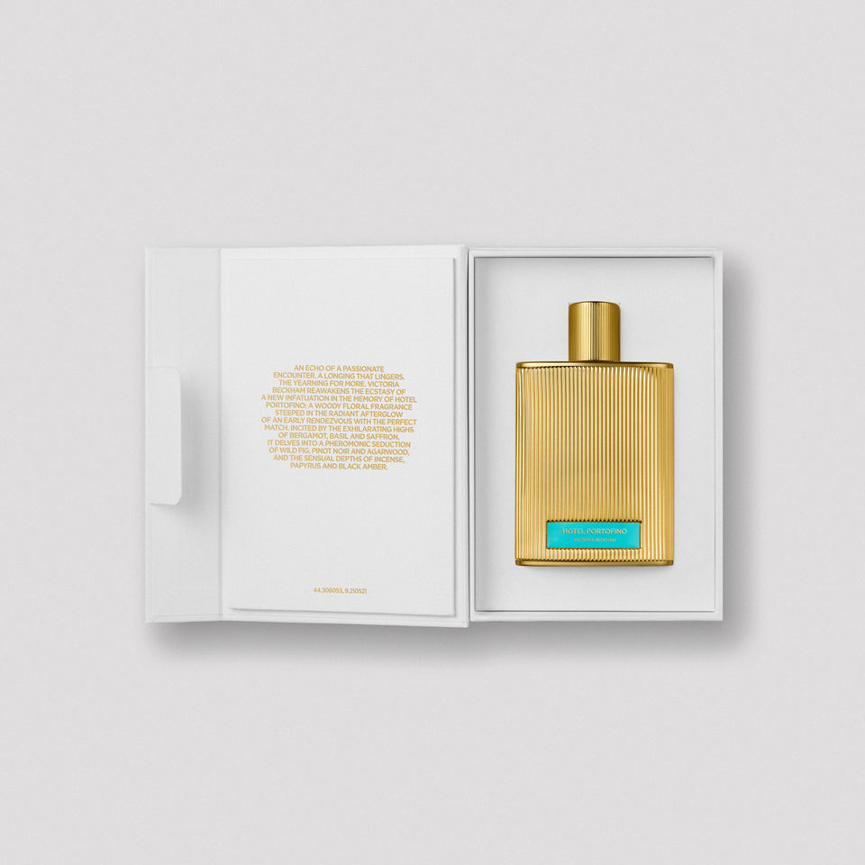 Open Hotel Portofino carton, gold bottle seated beside the printed scent story — the Extrait de Parfum by Victoria Beckham Beauty.