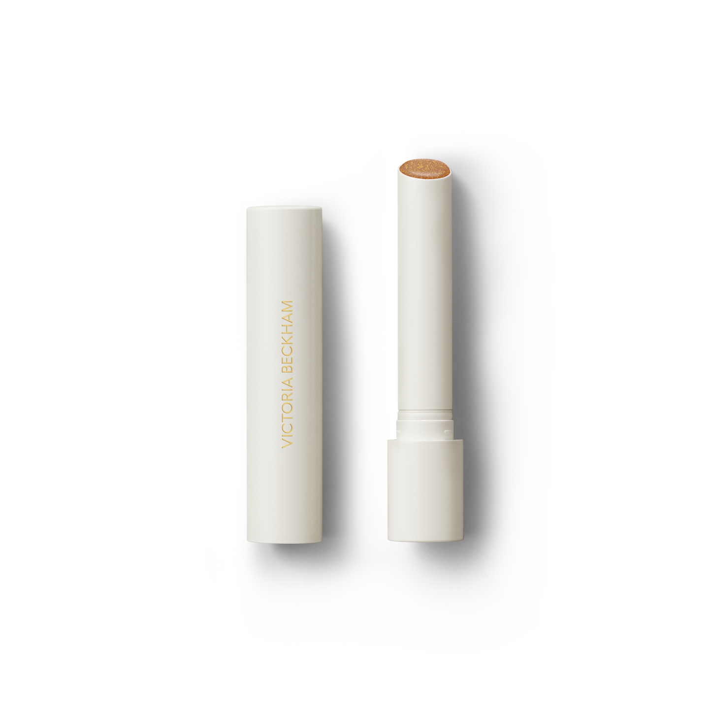 Open Victoria Beckham Beauty Posh Balm in Soleil — cream tube and cap beside the golden bronze shimmer balm bullet.