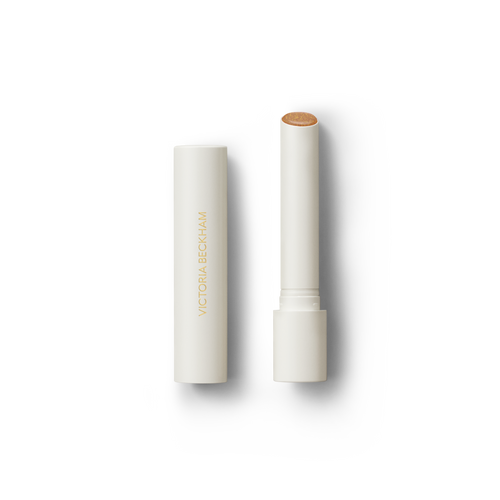 Open Victoria Beckham Beauty Posh Balm in Soleil — cream tube and cap beside the golden bronze shimmer balm bullet.