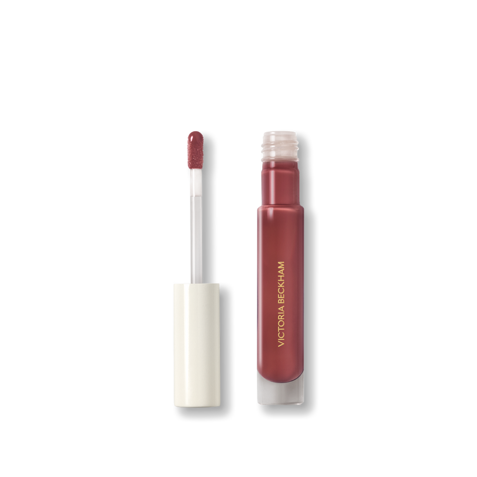 Open Victoria Beckham Beauty Posh Gloss tube in Aperitivo with doe-foot applicator wand revealing the rosewood-plum gloss.